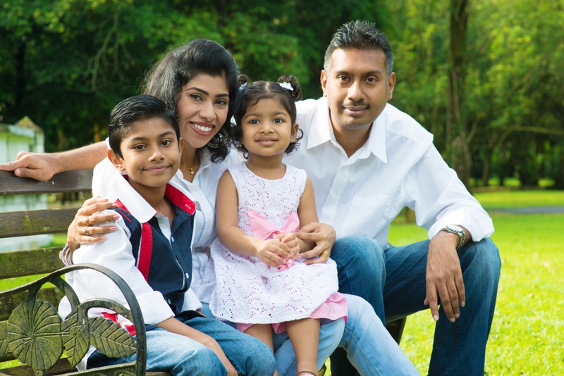 Smiling family sitting on park bench outdoors.