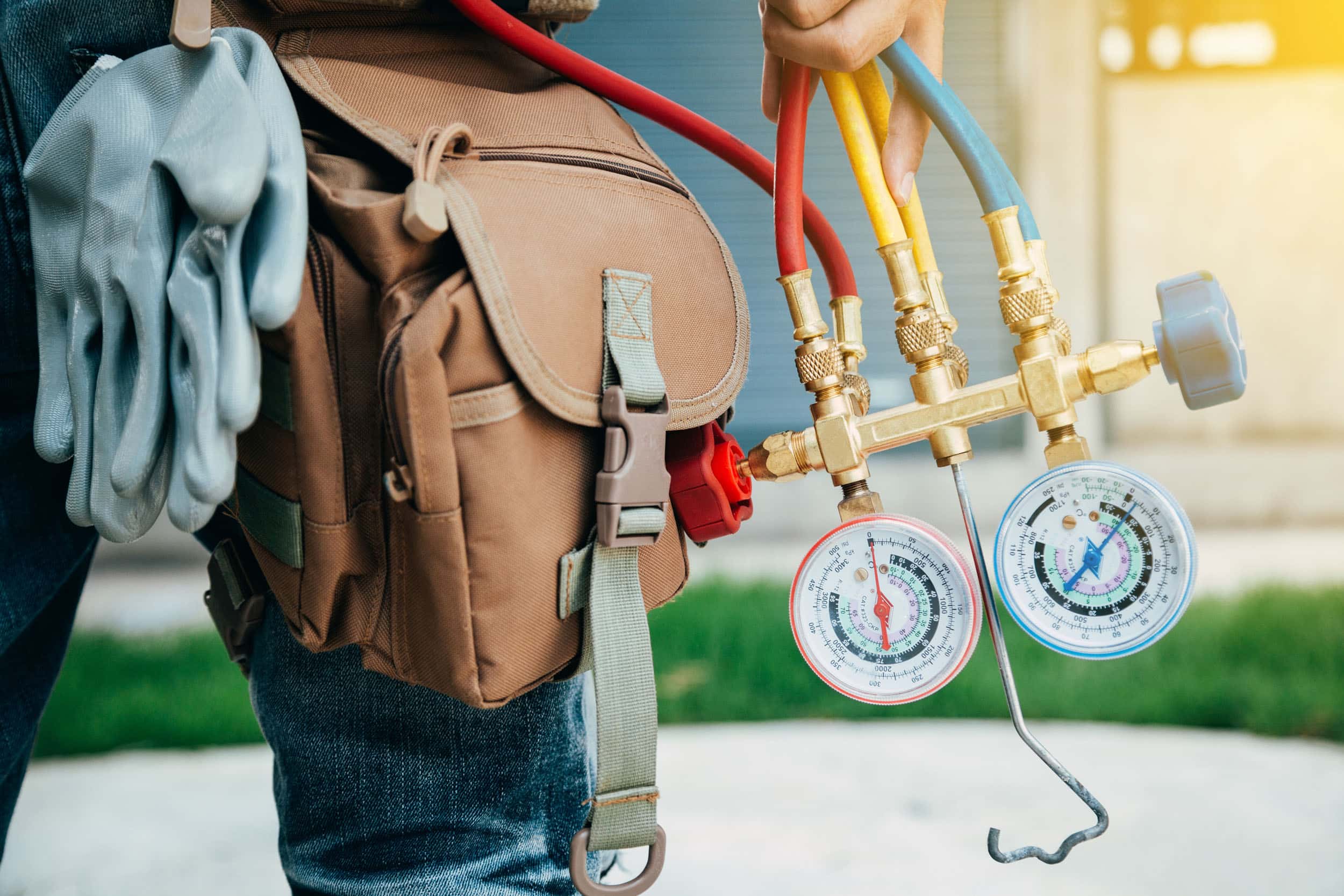 ac repair in conejo valley Technician holding HVAC gauges and tool bag