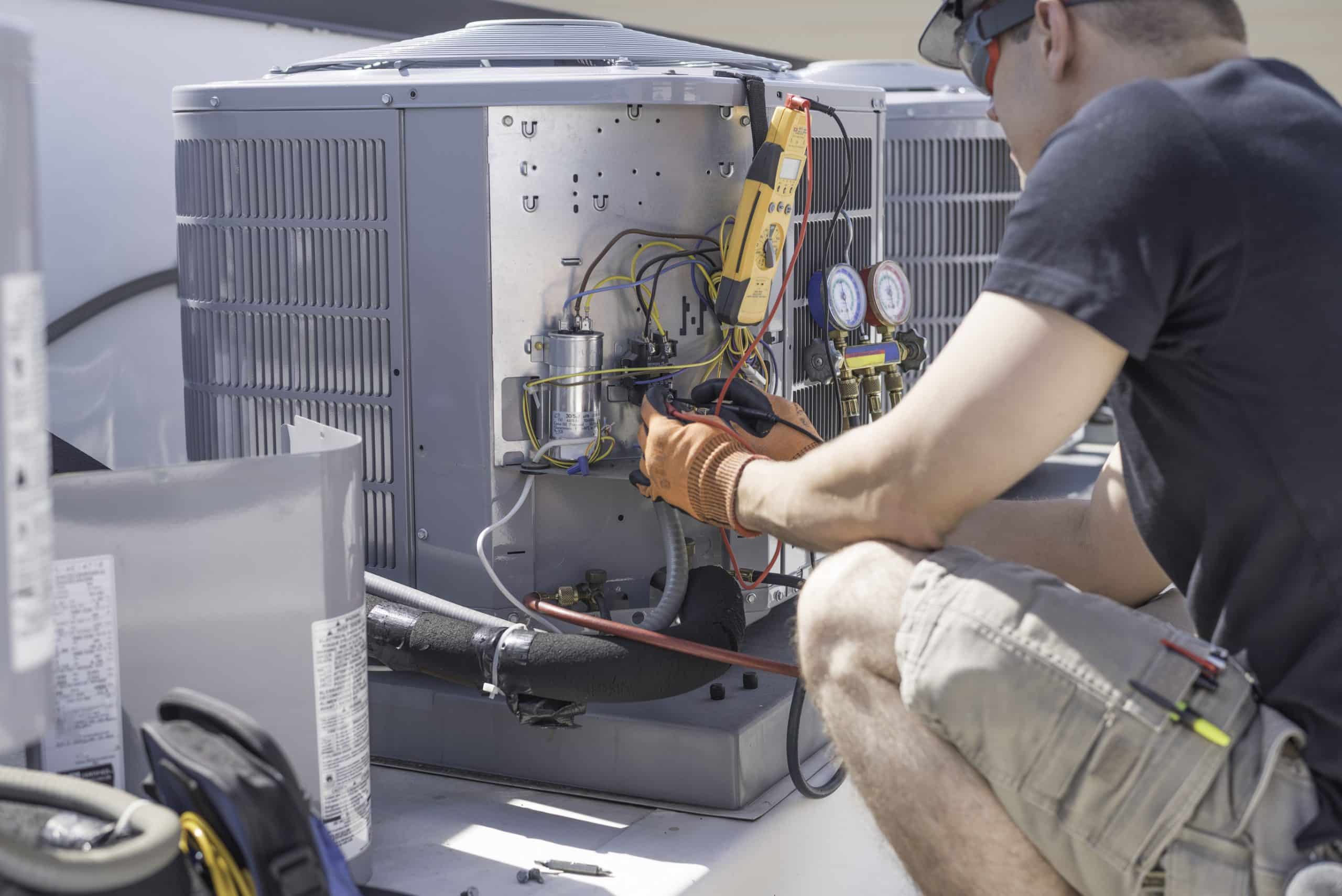 Technician repairing air conditioning unit outdoors.