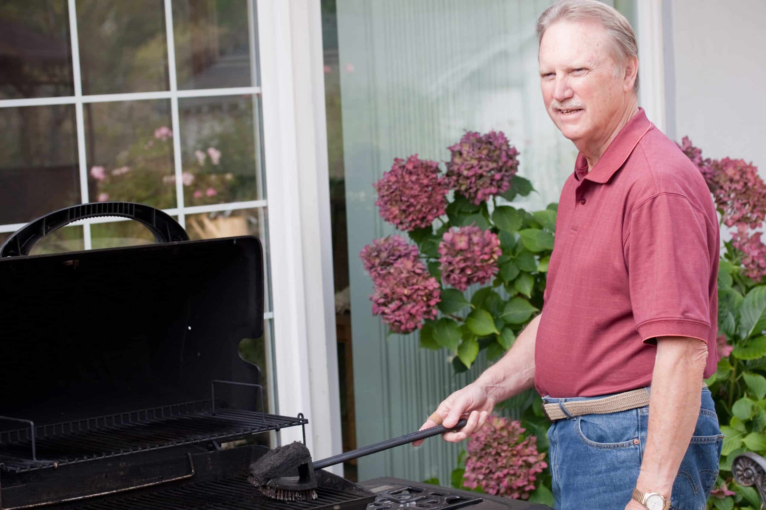 Man cleaning barbecue grill outdoors