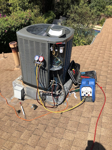 Air conditioning unit being repaired on roof.