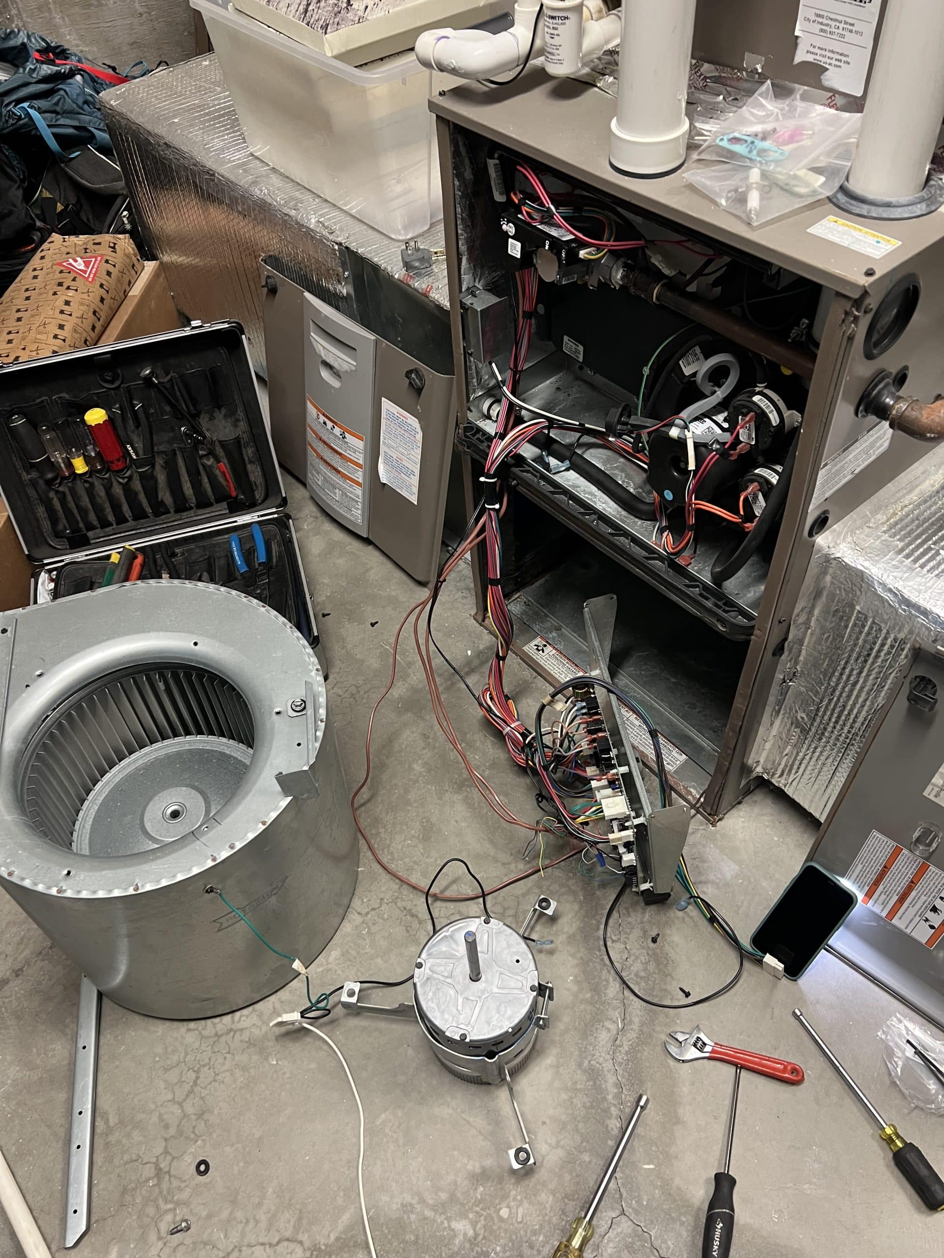 Disassembled HVAC unit with tools and wiring exposed.