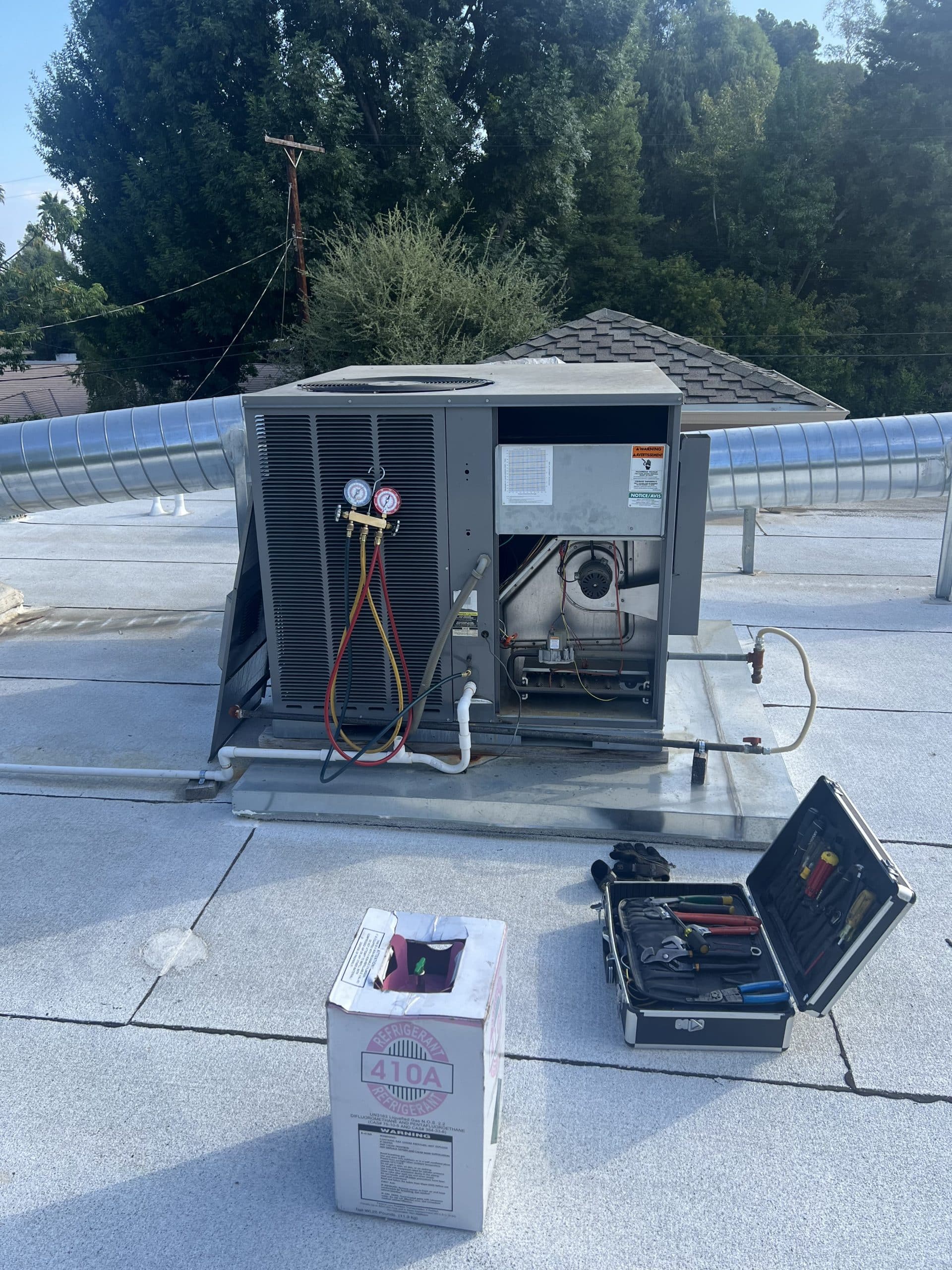 Rooftop HVAC unit maintenance with tools and refrigerant.